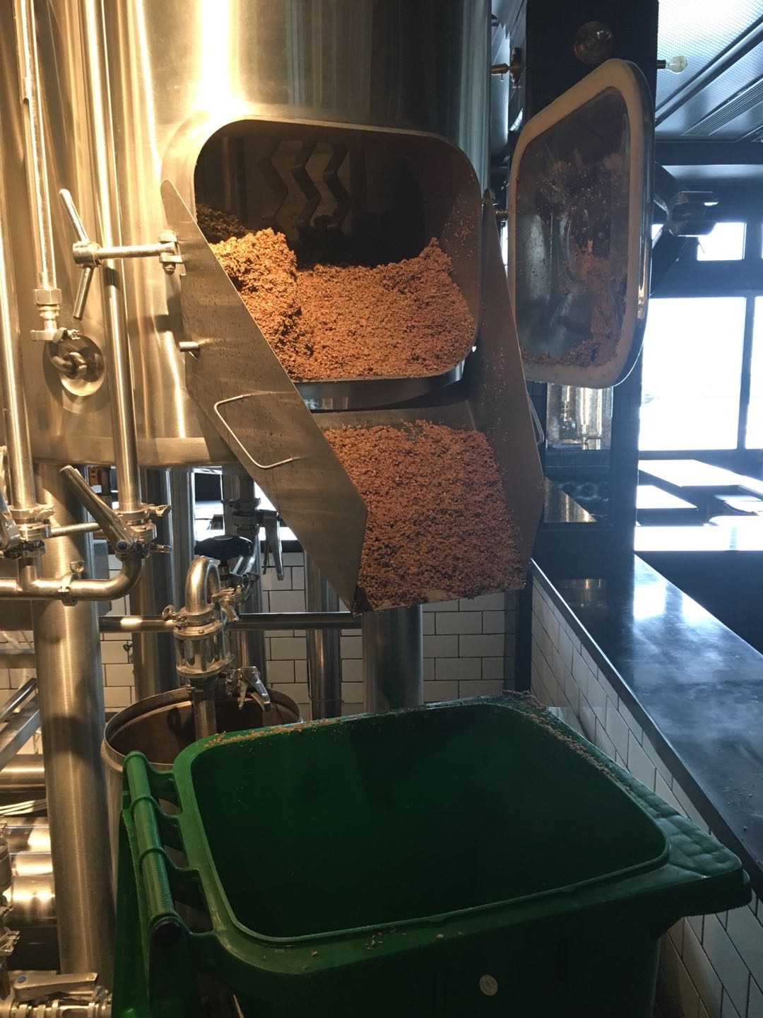 Brewpub bar atmosphere with brewing equipment visible behind glass